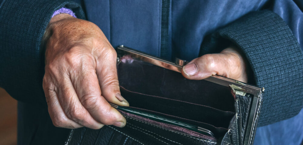 Empty wallet in the hands of an elderly woman. Concept of poverty. Shallow depth of field.